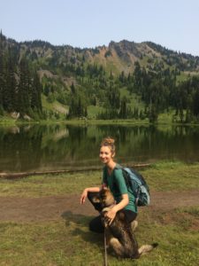 Kari kneeling with dog on a hike